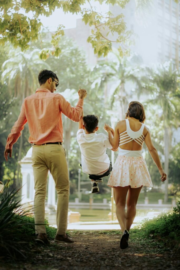 A family with a child enjoying a walk in a sunny park, creating joyful moments together.